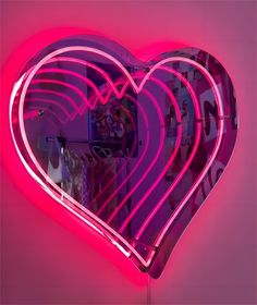 a heart shaped neon sign hanging from the side of a wall next to a mirror