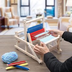 a woman is weaving fabric on a loom with yarn and crochet hooks