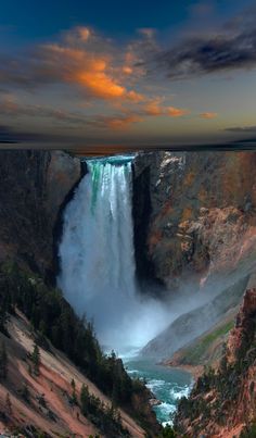 the sun is setting over a large waterfall