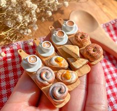 small miniature food items displayed in hand on table cloth with wooden spoons and flowers