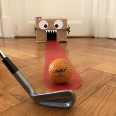 an orange golf ball sitting on top of a red mat next to a hole in the ground