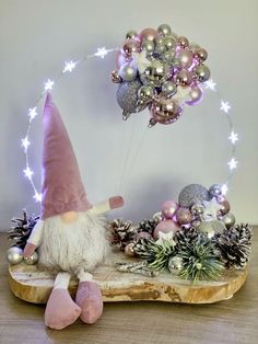 a gnome is sitting on a piece of wood with christmas decorations around him and his feet in the air