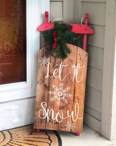 a wooden sign that says let it snow on the front porch next to a door