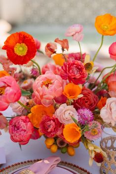 a vase filled with lots of colorful flowers on top of a table next to a plate