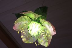 a flower hanging from the ceiling with green leaves and flowers on it's petals