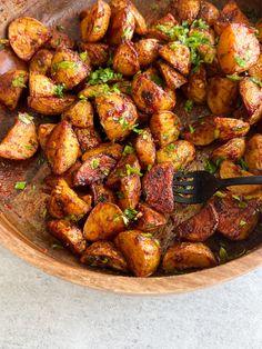 a wooden bowl filled with cooked potatoes and garnished with parsley