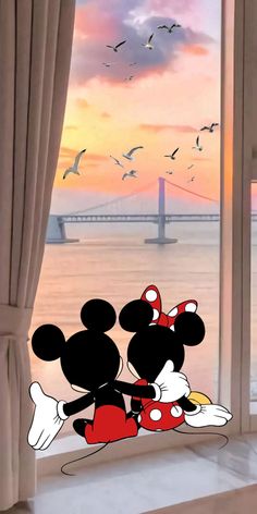 mickey and minnie mouse looking out the window at the sunset over the water with seagulls flying in the background