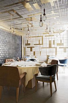 a dining room with chairs and tables in front of a metal wall that has squares on it