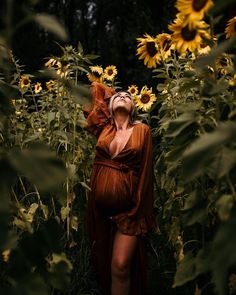 a woman in a brown dress standing among sunflowers