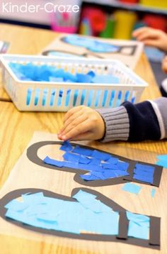 two children playing with construction paper at a table