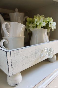 a white shelf with some cups and saucers on it