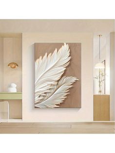 a large white feather is hanging on the wall in a room with wood flooring