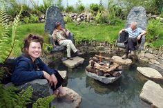 three people sitting on rocks near a pond