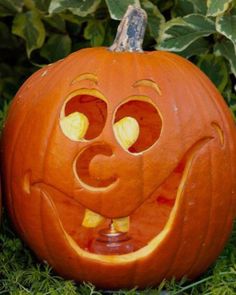 a carved pumpkin sitting in the grass with its mouth open and two eyes wide open