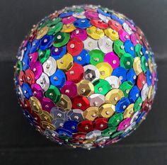 a multicolored ball with buttons on it sitting on a black surface, close up