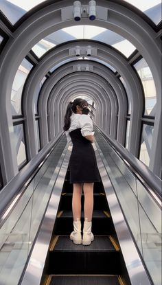 a woman is standing on an escalator with her back to the camera