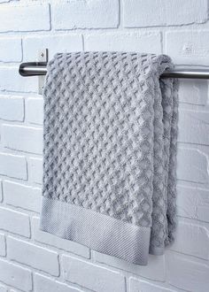 a gray towel hanging on a white brick wall