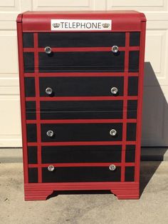 a red and black dresser sitting in front of a garage door with the word telephone on it