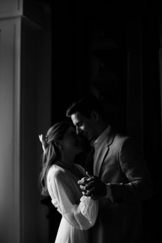 a man and woman dance together in the dark, black and white photo with their arms around each other