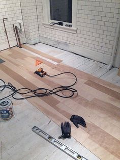 a room with hard wood floors and tools laying on the floor in front of it