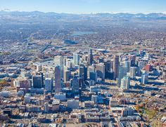 an aerial view of a large city with mountains in the backgrouund and snow capped mountains in the distance