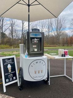 an ice cream machine sitting in the middle of a parking lot next to a sign