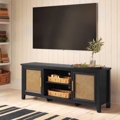 a black entertainment center with wicker baskets and a flat screen tv mounted on the wall