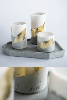 two white candles sitting on top of a tray next to each other with gold leaf designs