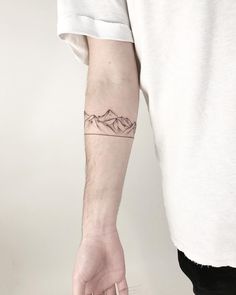 a man with a mountain tattoo on his arm is holding the hand of another person