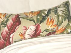 a pillow with flowers and leaves on it sitting on top of a white bed sheet