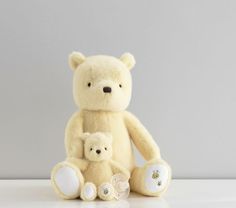 a teddy bear and its baby are sitting on a white countertop against a gray wall