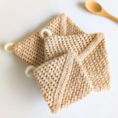 a crocheted dish cloth and wooden spoon rest on a white surface next to a pair of scissors