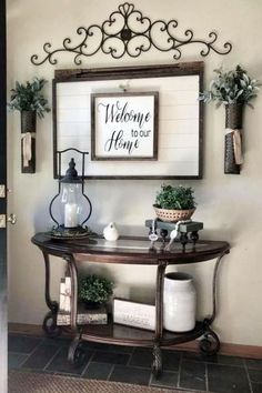 a welcome sign hangs on the wall above a table with potted plants and other decorations