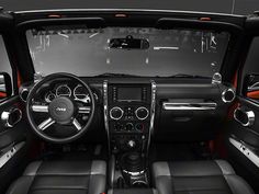 the interior of a vehicle with black leather and red trims, including steering wheel controls