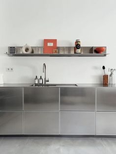 a kitchen with stainless steel cabinets and shelves on the wall, along with utensils