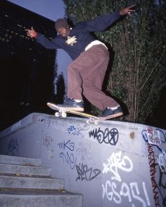 a man riding a skateboard up the side of a cement wall covered in graffiti