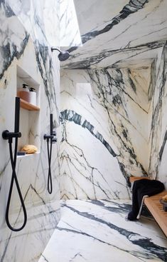 a bathroom with marble walls and flooring, including a walk - in shower area