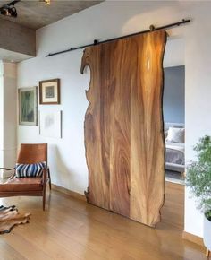 a living room with a wooden door and some pictures on the wall next to a chair