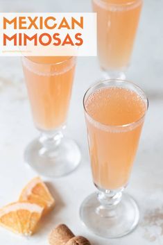 two glasses filled with mexican mimosa next to some sliced oranges and cinnamon sticks