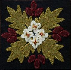 a close up of a piece of cloth with flowers and leaves in the center on a black background