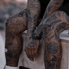 a man with tattoos sitting on top of a skateboard