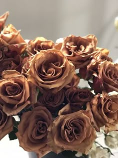 a vase filled with lots of brown roses