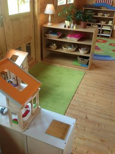 a toy house on top of a table in a room with wooden floors and walls