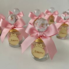 four small jars with pink bows and nameplates on the top one is empty