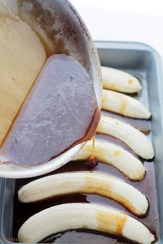 bananas are being drizzled with caramel sauce on a baking pan filled with chocolate