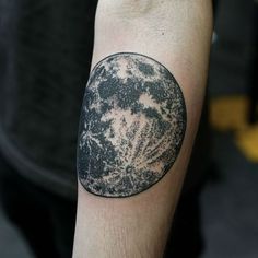 a man's arm with a black and white moon tattoo on it