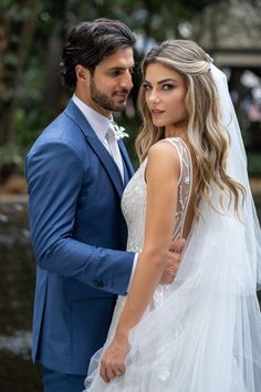 a bride and groom pose for a photo in front of the waterfall at their wedding