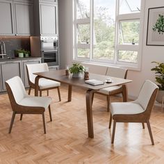 a dining room table with four chairs and a potted plant in the center, on a hard wood floor