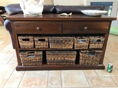 a brown couch sitting next to a wooden table with baskets on it