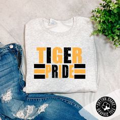 Our brand new school spirit sweatshirt Show your school spirit with this ash crewneck sweatshirt! Accented with a yellow and black design, this unique garment is sure to turn heads and have your friends shouting 'Go Tigers!' Features: multi color design on ash crewneck sweatshirt design is DTG pressed unisex fit runs true to size Brand: Gildan ﻿Use code: PICKUP at checkout for local pickup Crewneck Sweatshirt Design, Booster Club, Spirit Shirts, Sherpa Pullover, New School, Yellow And Black, Crew Sweatshirts, School Spirit, Sweatshirt Designs